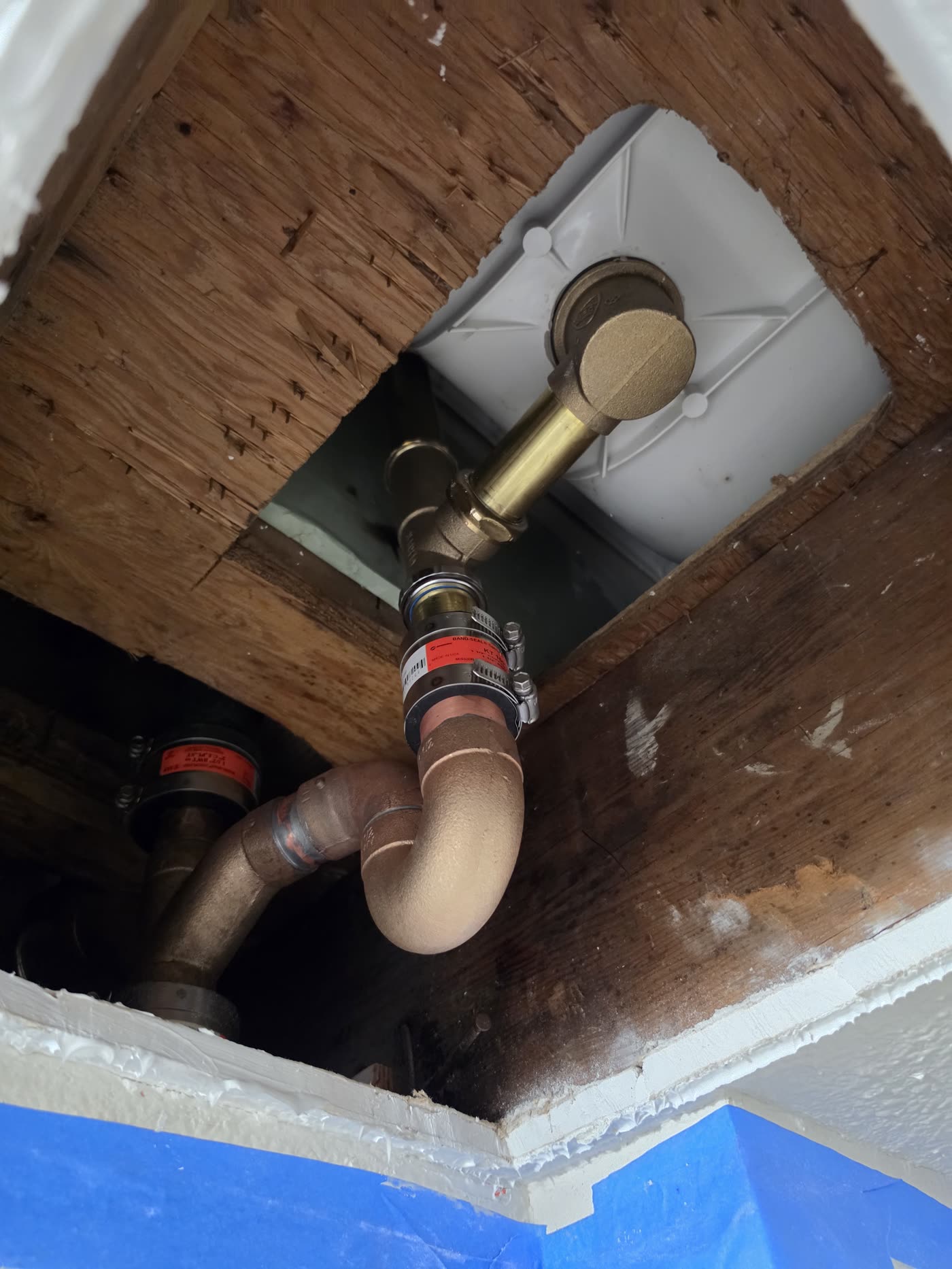 New brass drain connection installed below a floor