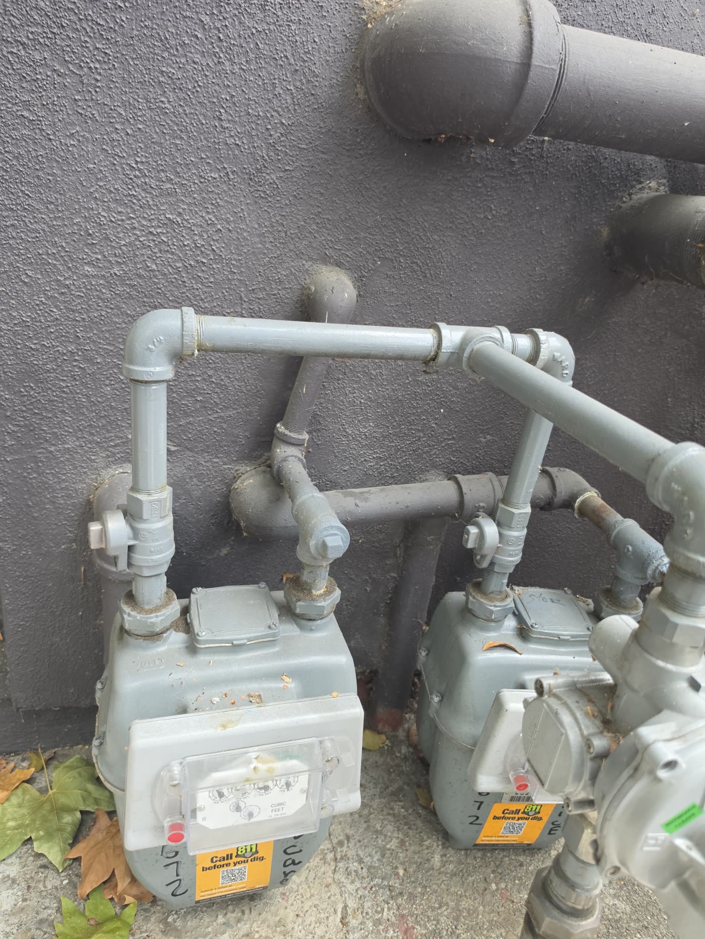 Two exterior gas meters with connected plumbing