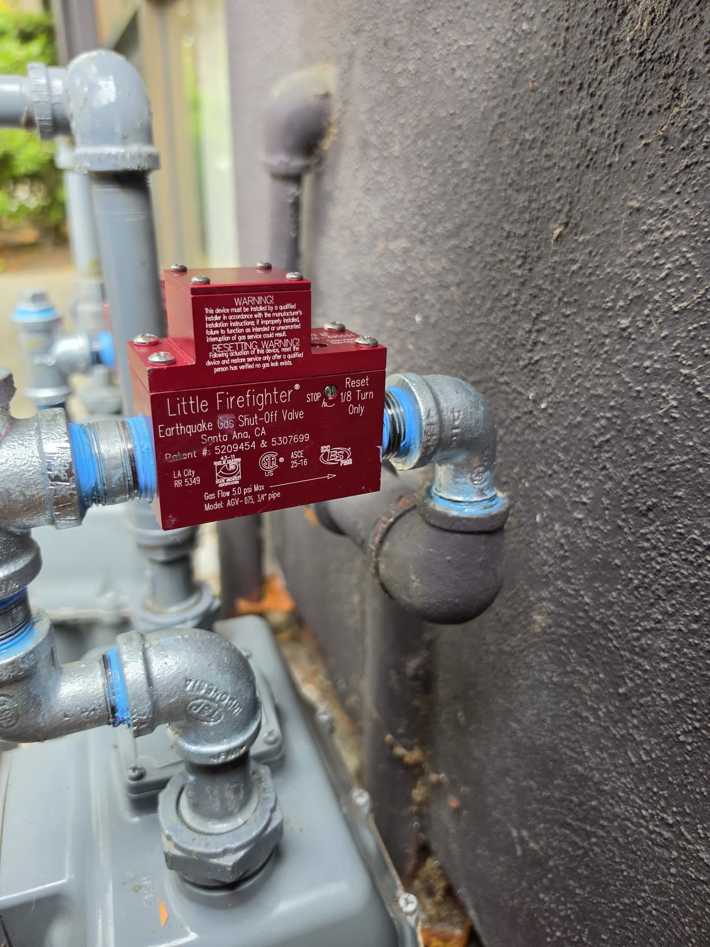 Close view of gas piping and a red shutoff valve